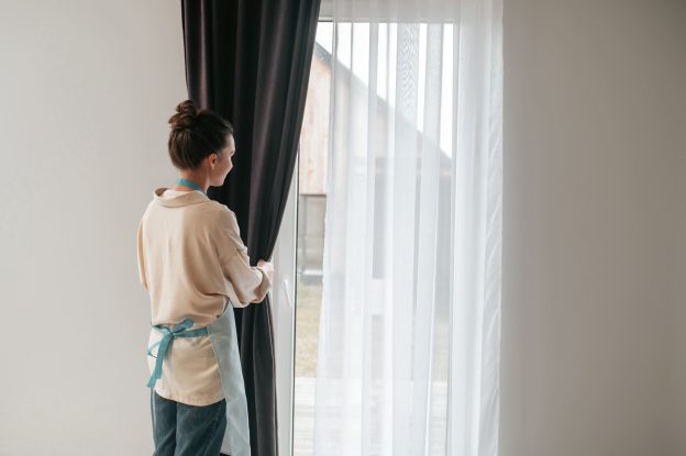 Pessoa abrindo cortina blackout em ambiente interno após limpeza e manutenção adequada