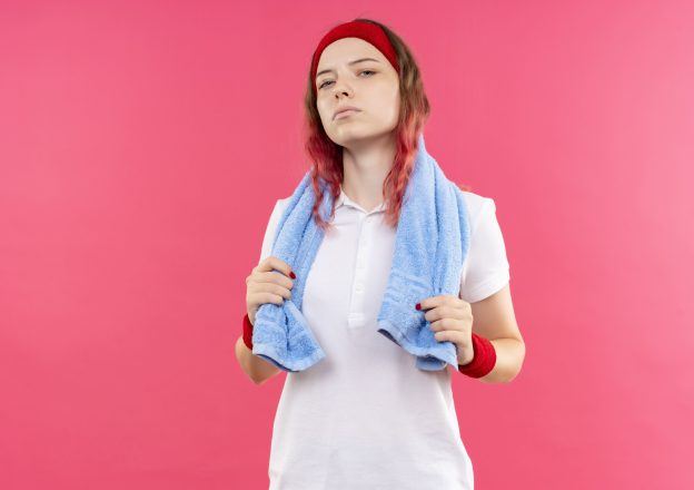 Pessoa com roupa de academia após treino segurando toalha, relacionada à lavagem de roupas esportivas